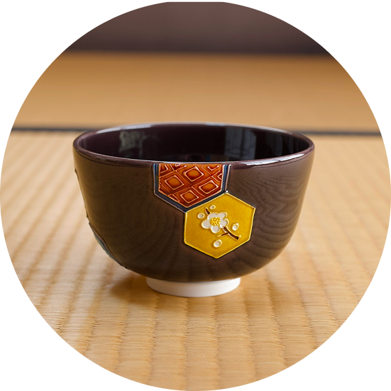 六角形の黄色と赤の模様がある茶色い湯呑が畳に置かれている